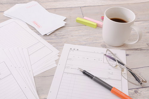 記入する前の履歴書の山とデスク周りの文房具