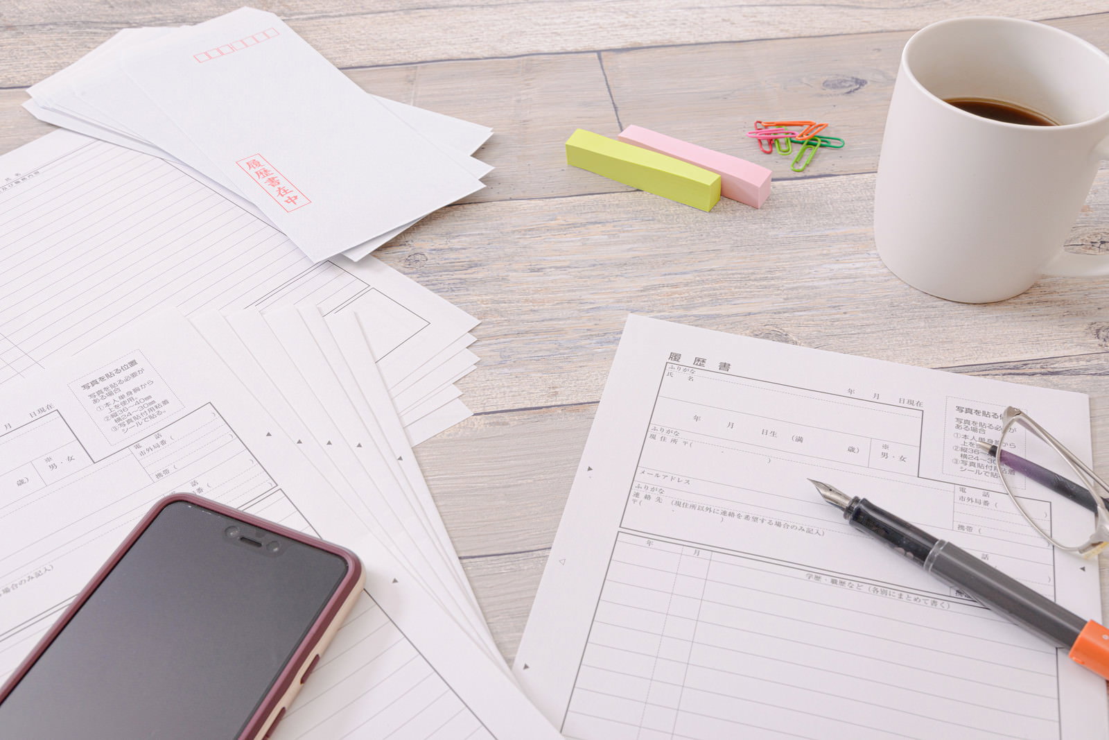 Desk with scattered documents, a coffee cup, and a smartphone