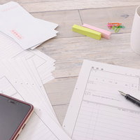 書き出せない履歴書とコーヒーが置かれたデスクの写真