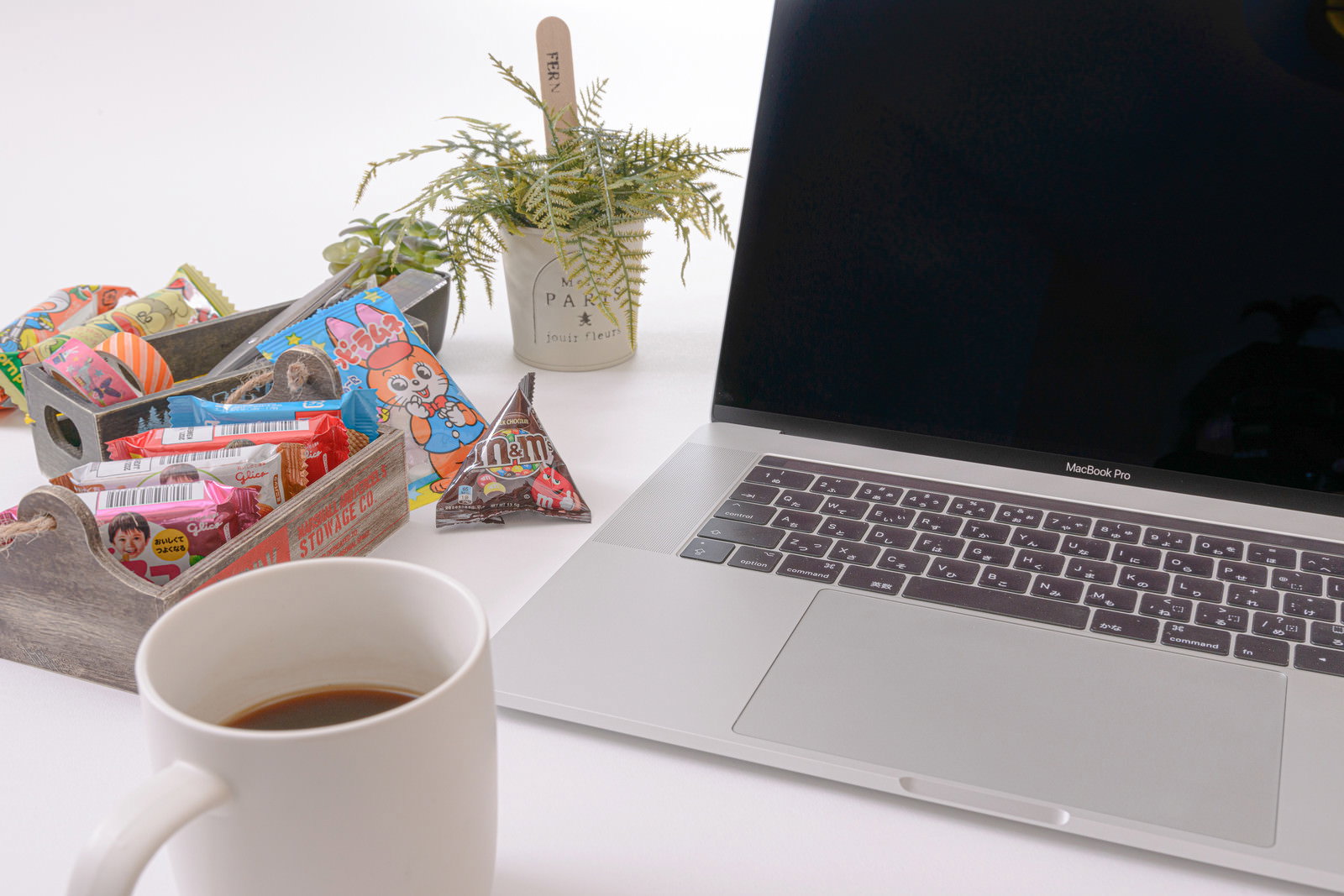 デスクでお菓子を食べながらMacbookで作業する様子