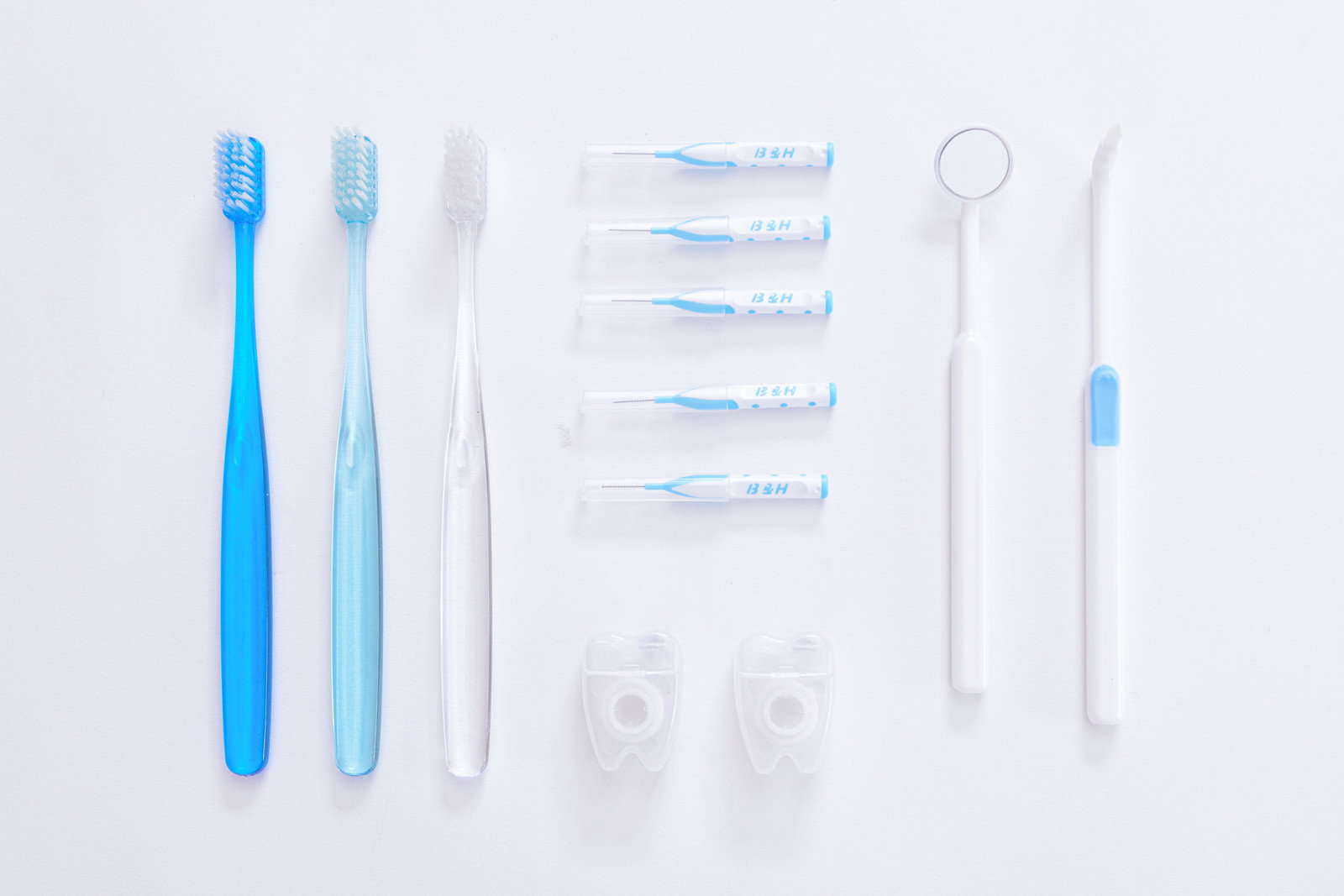 白い背景に並べられた青と白の歯ブラシと歯間ブラシのデンタルケアセット