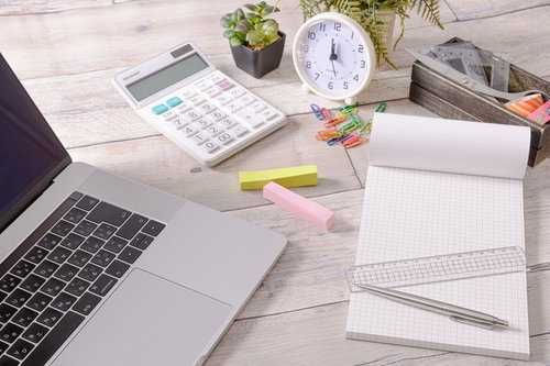 無造作に置かれた文具とノートパソコンのデスク風景