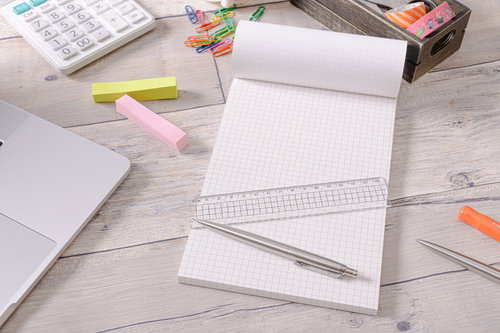 白いデスクに並ぶ方眼ノートと定規とペンと付箋