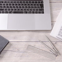 デスクワークに必要な文房具類と電卓、ノートパソコンの写真