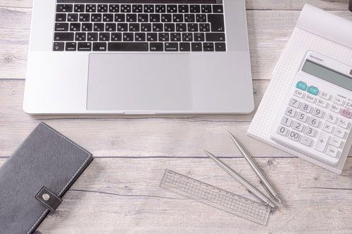 デスクワークに必要な文房具類と電卓、ノートパソコン