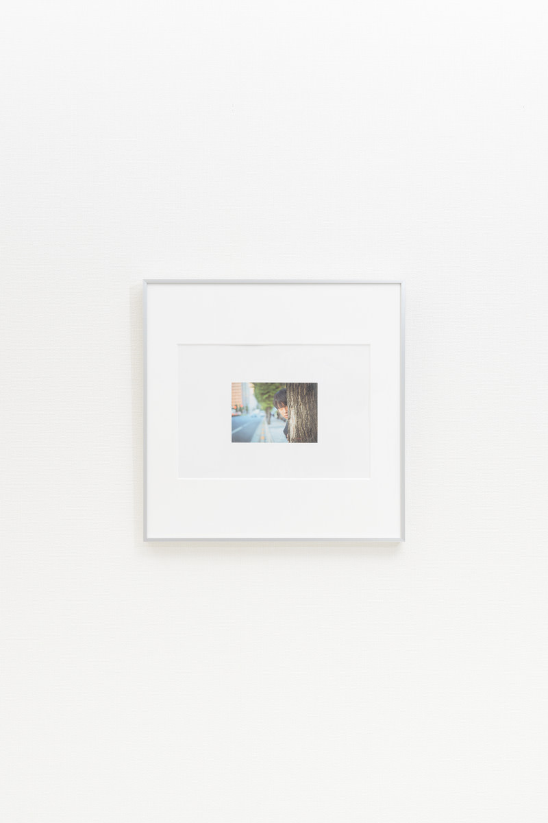 白い壁に掛けられた白いフレームの額縁［モデル：大川竜弥］