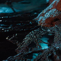 備中鐘乳穴の鍾乳石に絶えず滴る水と青白く反射する光の写真