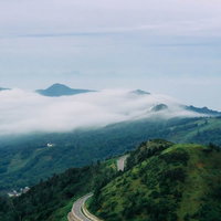 万座高原の流れるような雲海と山道を彩る朝霧の風景の写真