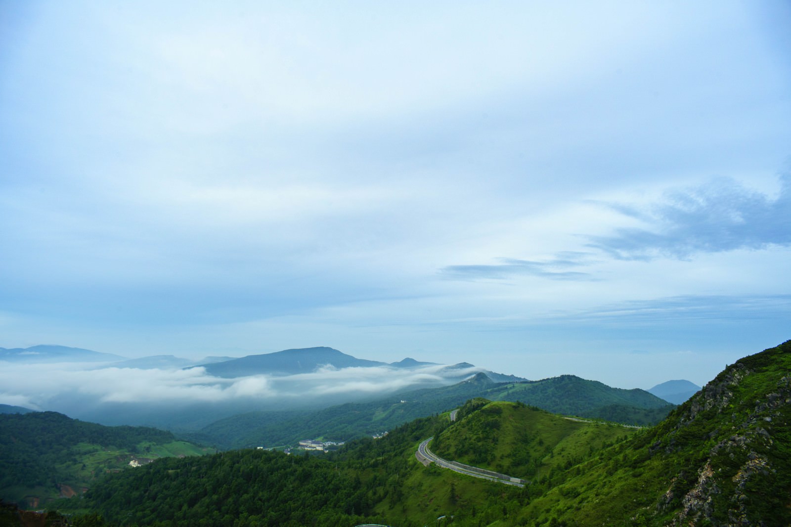 草津白根山の山頂から見下ろした万座温泉と周囲の山々の風景