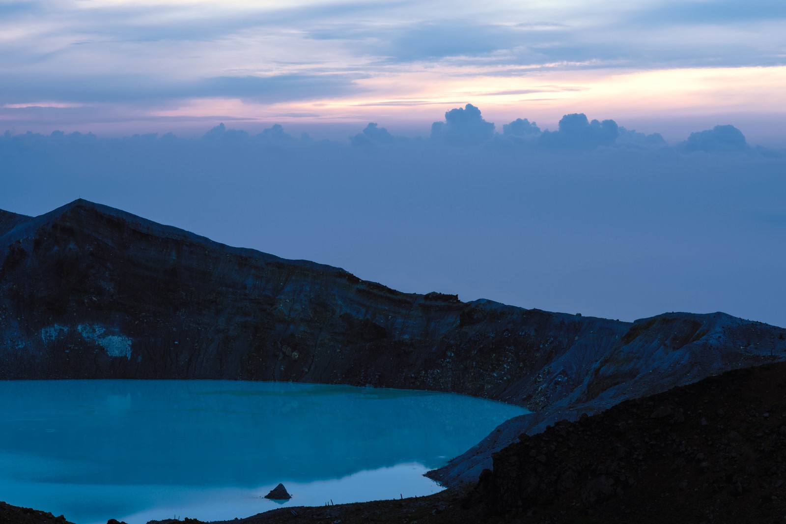 朝焼けの空に浮かぶ白根山の湯釜と山々のシルエット