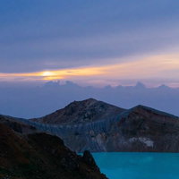 白根山の湯釜と朝焼け：日の出時の火口湖の絶景の写真