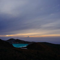 エメラルドグリーン色の湯釜と夜明けの空の写真