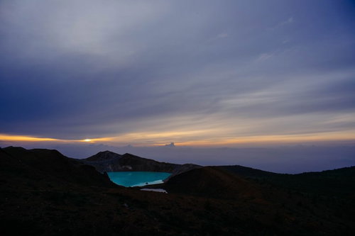 エメラルドグリーン色の湯釜と夜明けの空