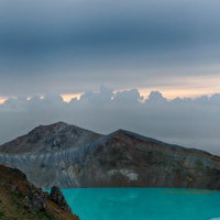 朝焼けに染まる湯釜のエメラルド色と白根山の絶景の写真