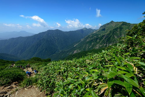 関東と北陸を隔てる稜線の登山道を歩く登山者