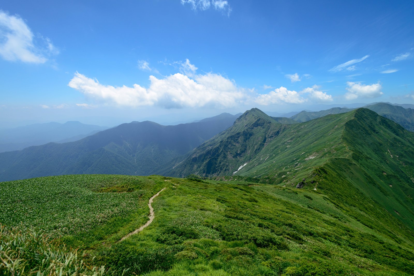 谷川岳の稜線を歩く登山道と青空に浮かぶ白い雲の風景