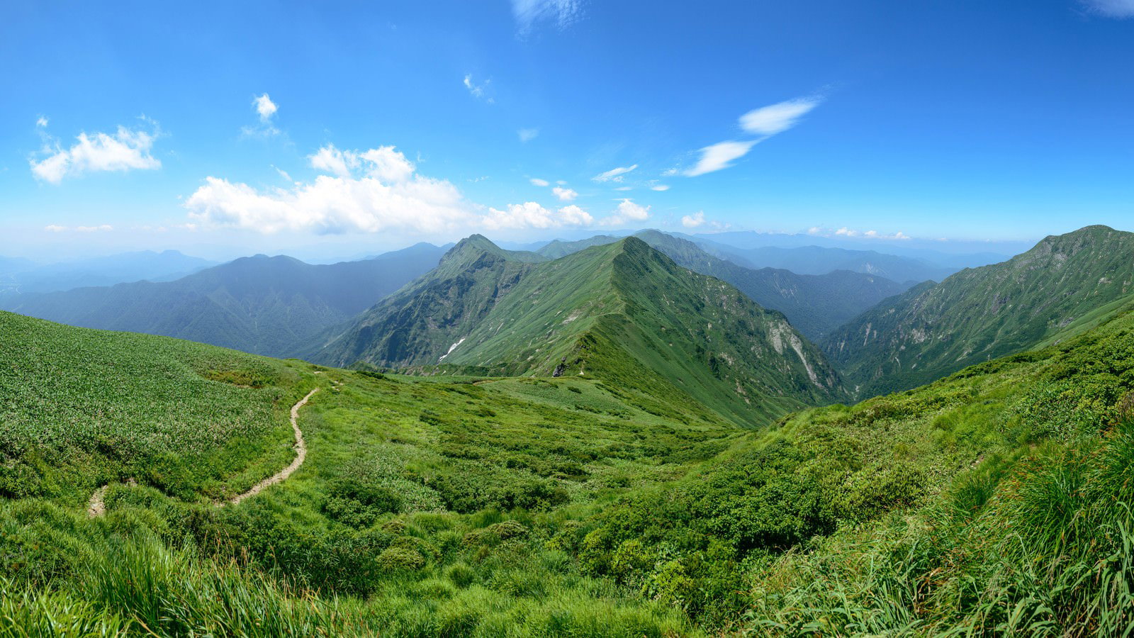 谷川岳主脈の緑豊かな稜線に沿って続く登山道と青空