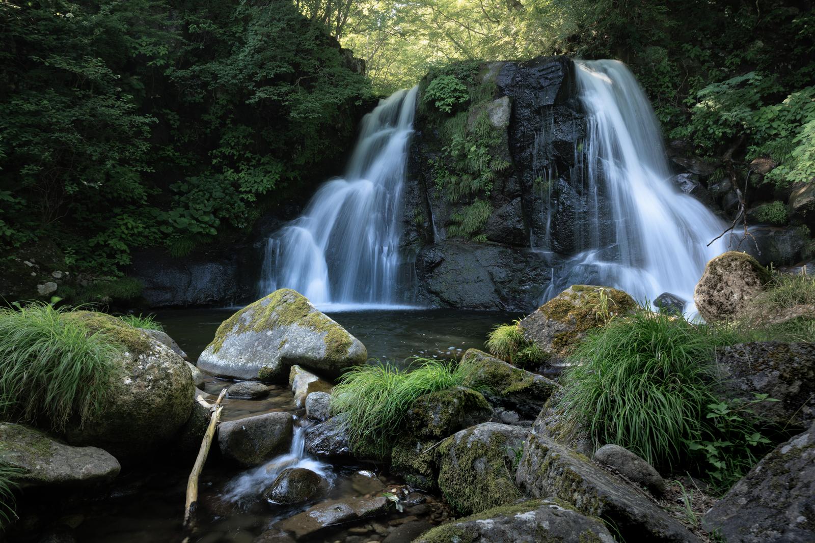 天栄村の明神滝で、苔むした岩から流れ落ちる白い水が滝壺に落ちる景観