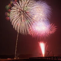 浅川町の夜空に咲く打ち上げ花火の光跡と夏祭りの情景の写真