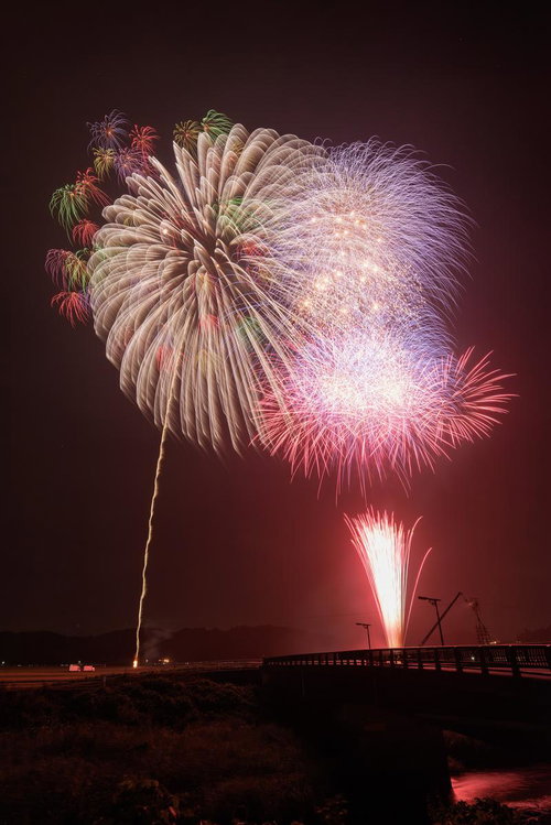 浅川町の夜空に咲く打ち上げ花火の光跡と夏祭りの情景