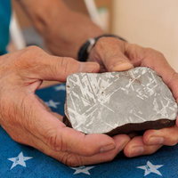 数億年かけて宇宙でできたニッケルと鉄の結晶を手のひらに乗せた隕鉄の写真