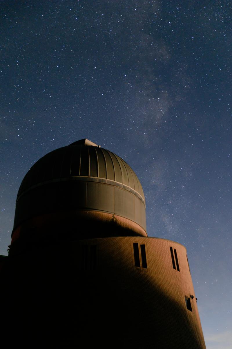 ドーム型の天文台を照らす夜空に天の川が流れる星景写真