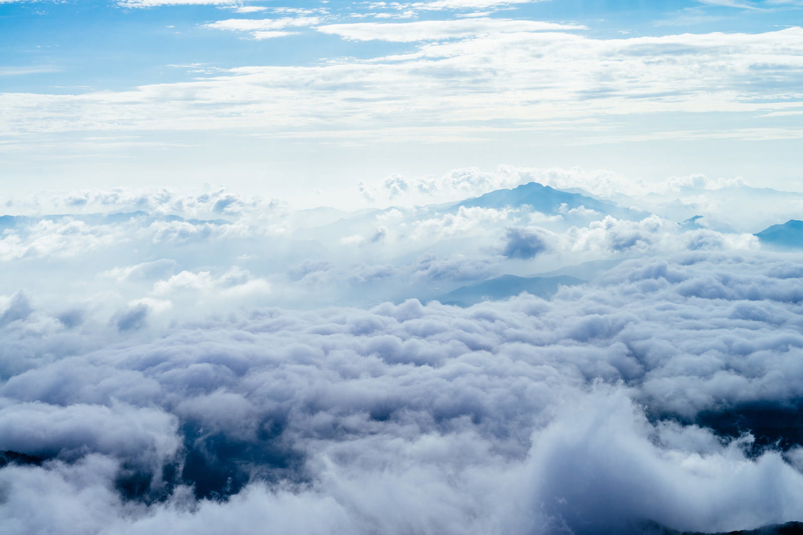 雲海の上に浮かぶ山々のシルエットと青空が広がるにゅうからの景色