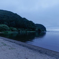 曇り空の下に静かに佇む猪苗代湖の秋山浜の写真