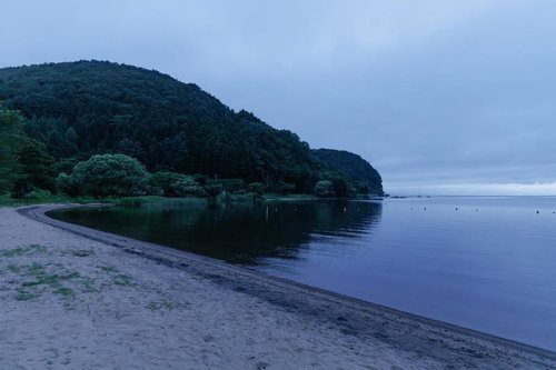 曇り空の下に静かに佇む猪苗代湖の秋山浜