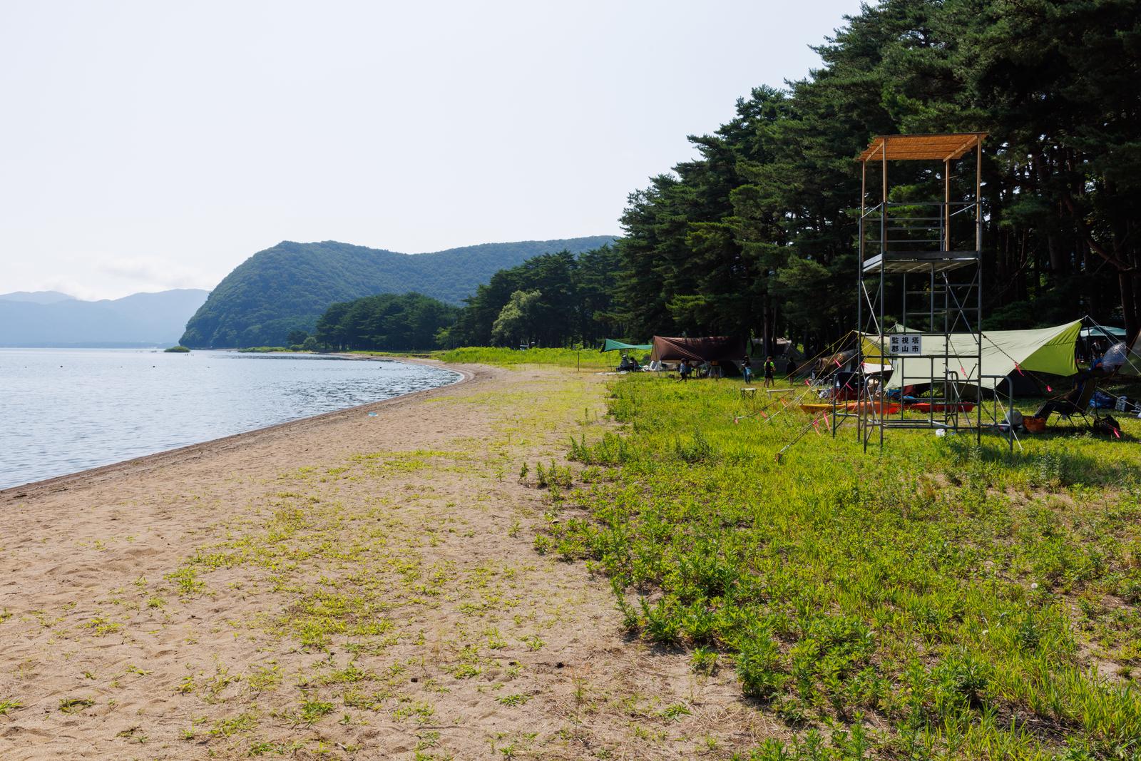 猪苗代湖の湖岸に立つテントと組立台が見えるキャンプサイト