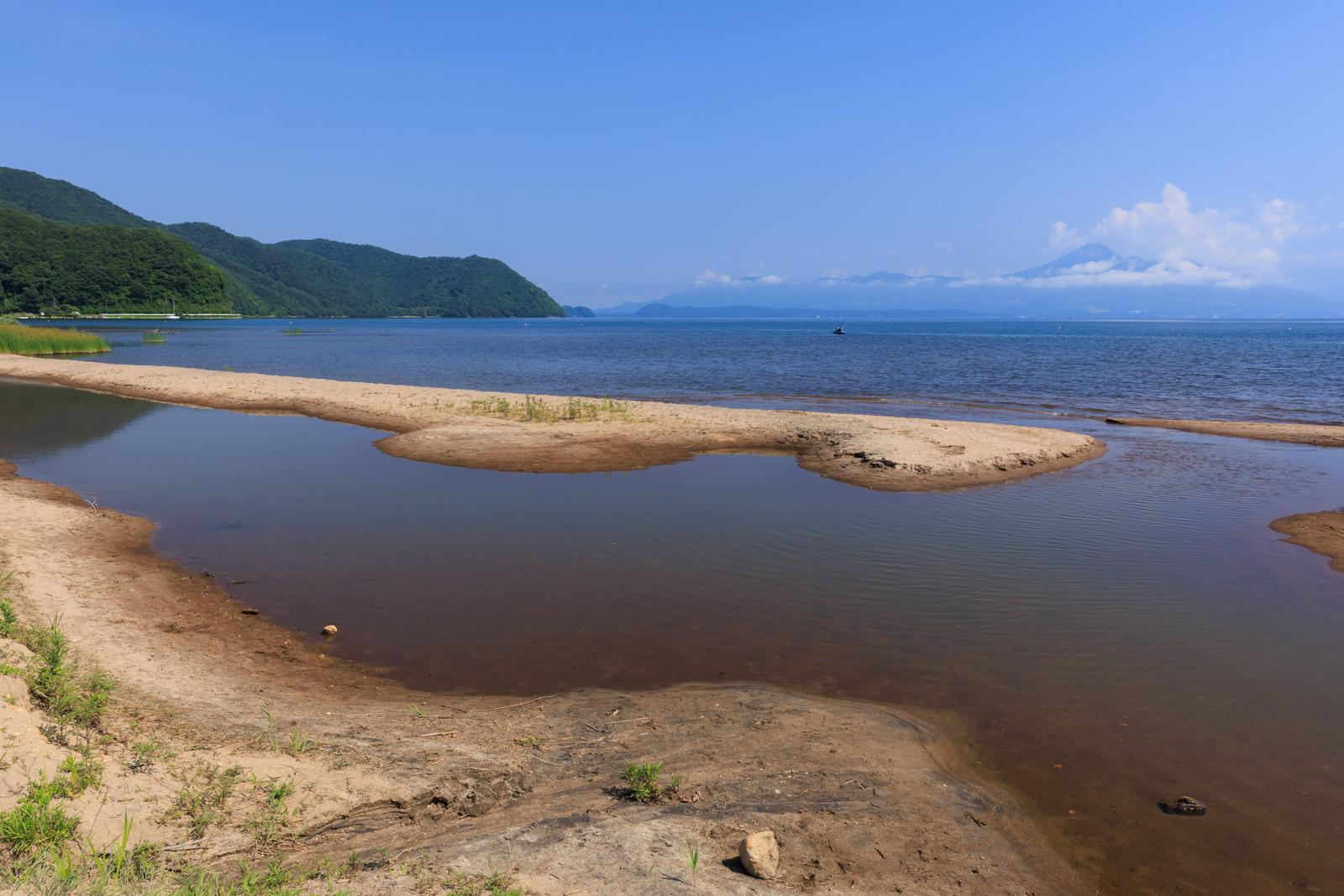 磐梯山を背景に白い砂浜と流木が横たわる猪苗代湖の青松浜