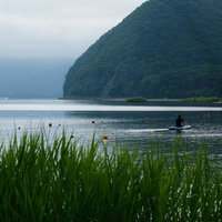 猪苗代湖でSUPを楽しむ人と緑豊かな山々の風景の写真