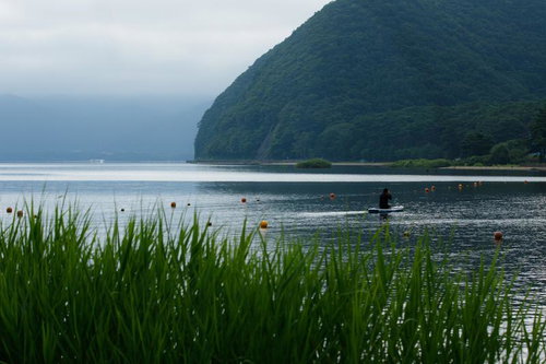 猪苗代湖でSUPを楽しむ人と緑豊かな山々の風景