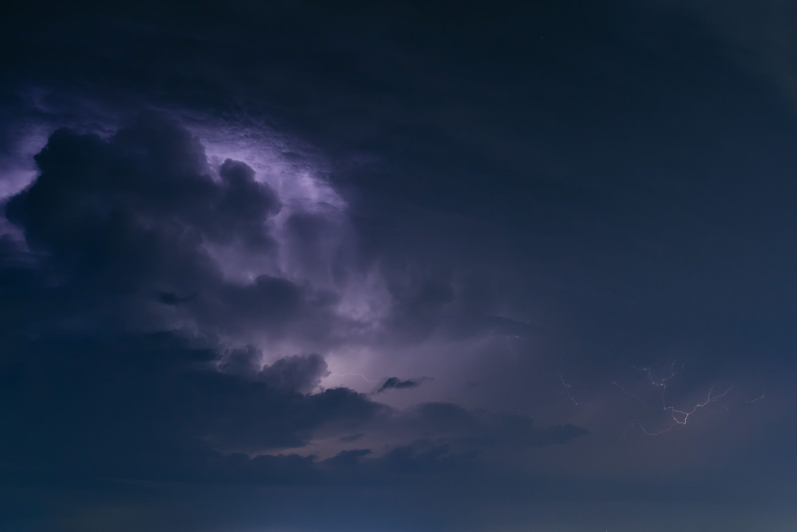 暗い夜空に紫色の雷雲が広がっている様子
