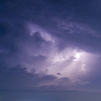 暗い夜空に紫色の稲妻が走る雷雲と積乱雲による激しい嵐の写真