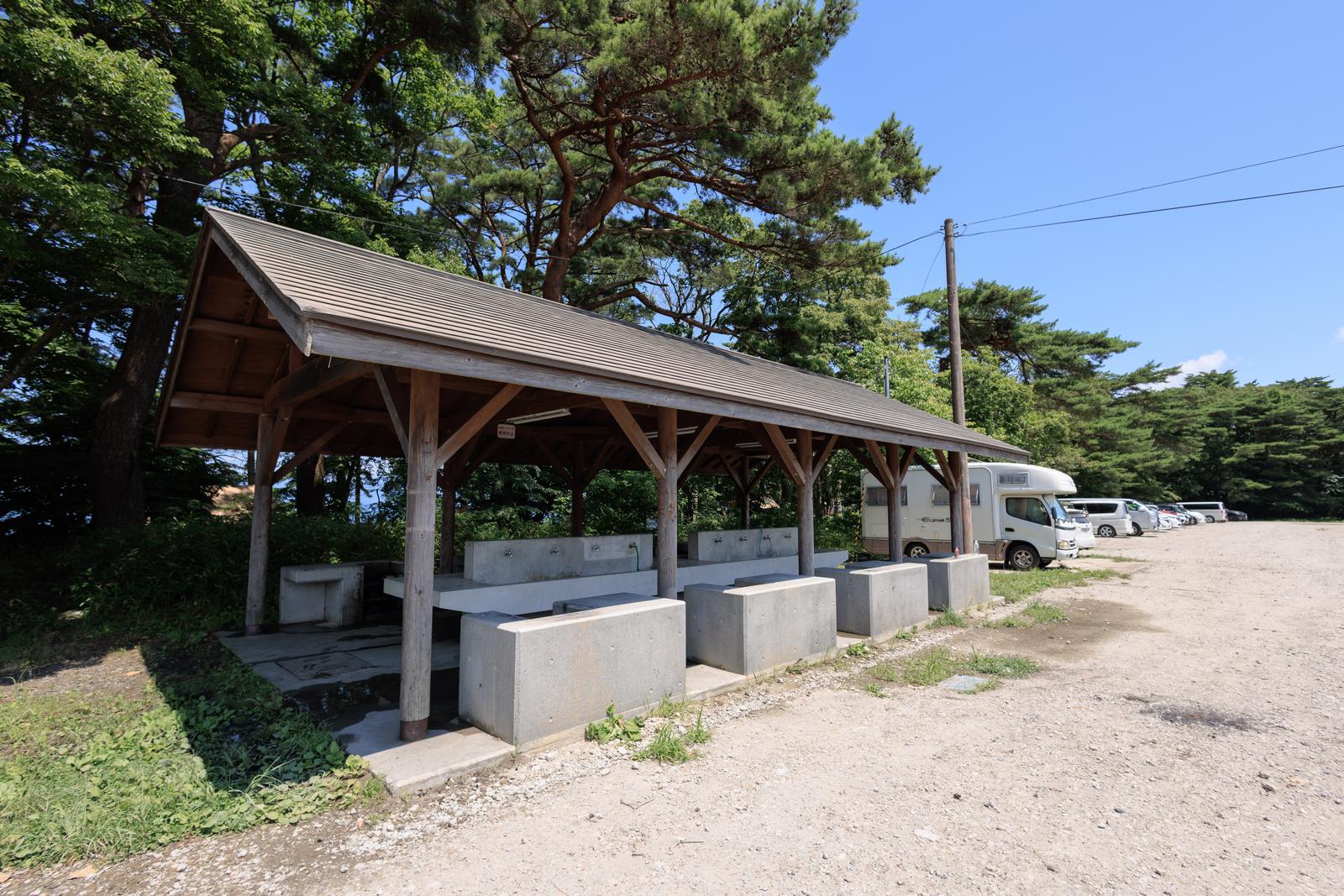 郡山市横沢浜キャンプサイトの屋根付き炊事場。木製の梁とコンクリート製の調理台