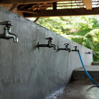 横沢浜の炊事場に並ぶ複数の蛇口と青いホースの写真