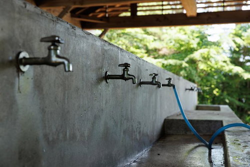 横沢浜の炊事場に並ぶ複数の蛇口と青いホース