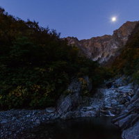 満月が覗き込む群馬県みなかみ町一ノ倉沢の夜景の写真