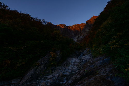 夕暮れ時の一ノ倉沢、険しい岩壁に続く沢と河原の渓谷風景