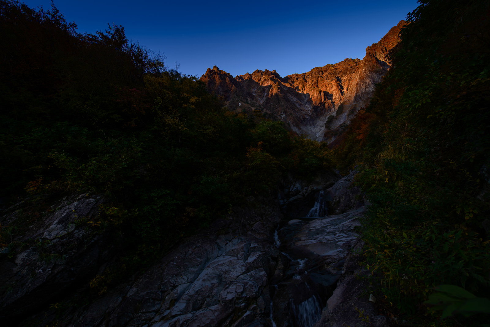 群馬県一ノ倉沢の朝日に照らされた巨大な岩壁と沢の風景