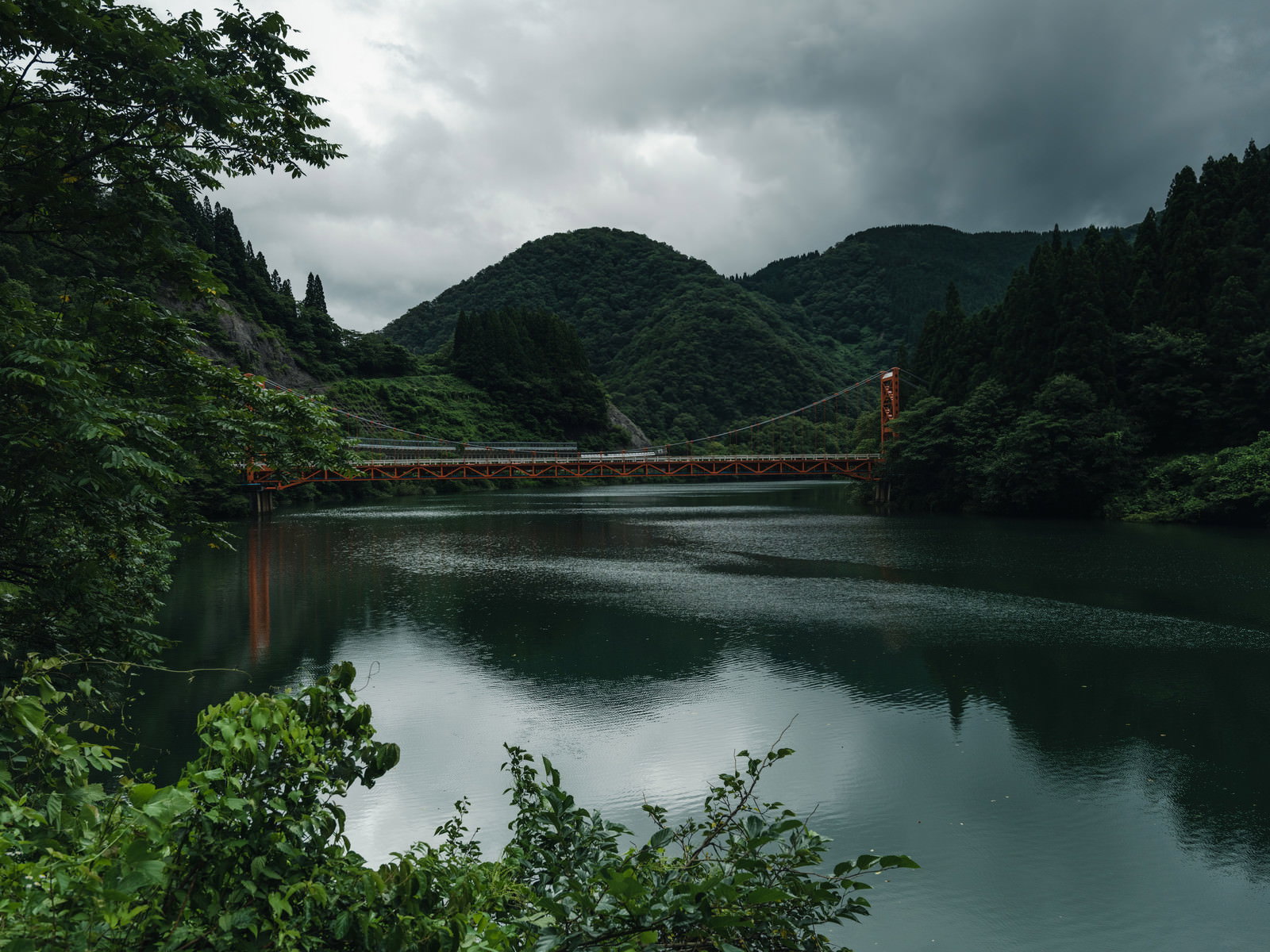 庄川峡の静かな水面に橋が映り込み、緑の山々に囲まれた風景