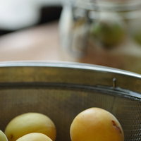 水切り中の梅とステンレスざるの写真