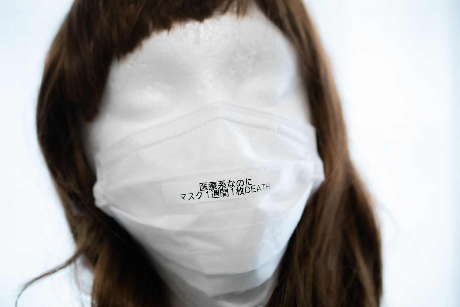白いマスクを着用した茶色い髪の人形