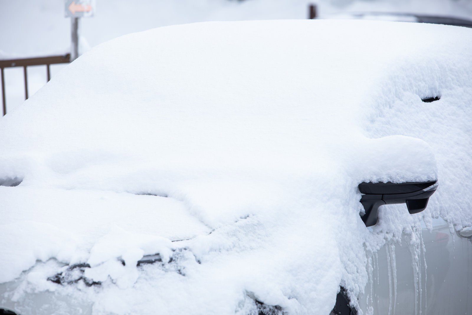 雪に覆われた車が駐車場に停まっている冬の風景