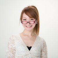 赤い眼鏡をずらして笑うレース服の女性の写真