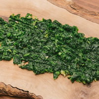 木のまな板の上に細かく刻まれたセリのの写真