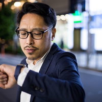 予定時刻5分前に腕時計を確認する不安な男性の写真
