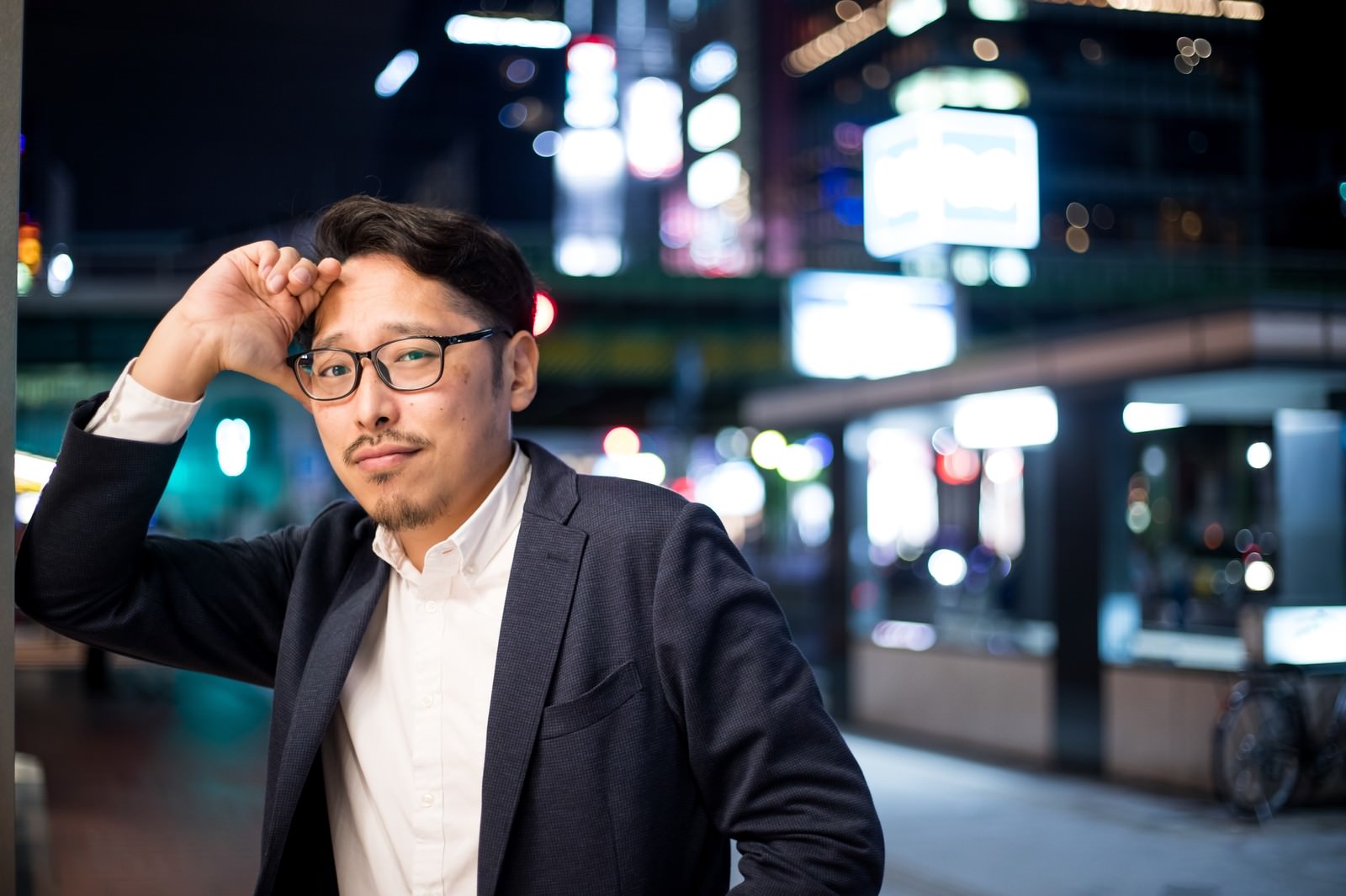 夜の街でポーズを決める眼鏡をかけたスーツ姿の男性
