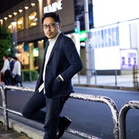 会社帰りに駅前で待ち合わせするスーツ姿の男性の写真
